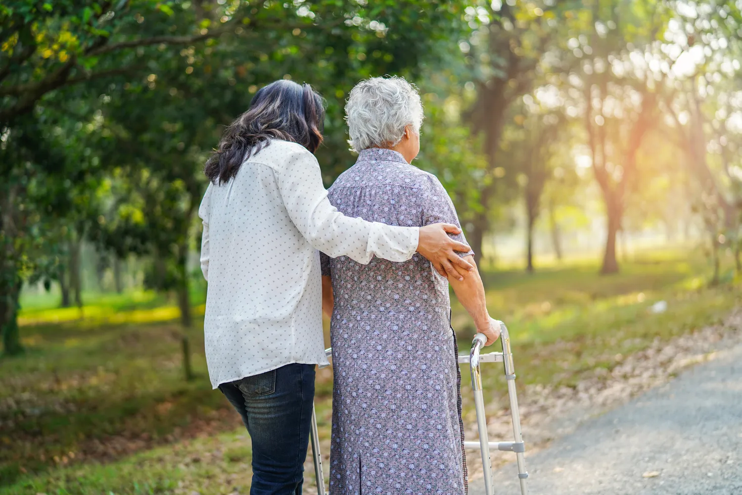 SENIOR GOLD 24 GMBH, Krankenschwester hilft einer alten Dame beim Gehen mit Hilfe einer Gehhilfe
